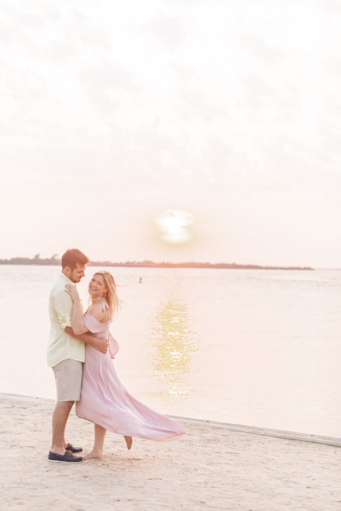 A couple at the beach laughing displaying what to wear to your engagement session
